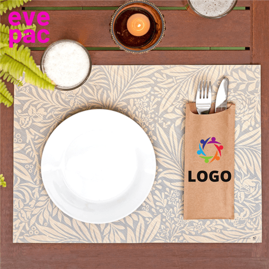Pochette à couverts personnalisée en papier Kraft sur une table dressée élégamment avec logo visible.
