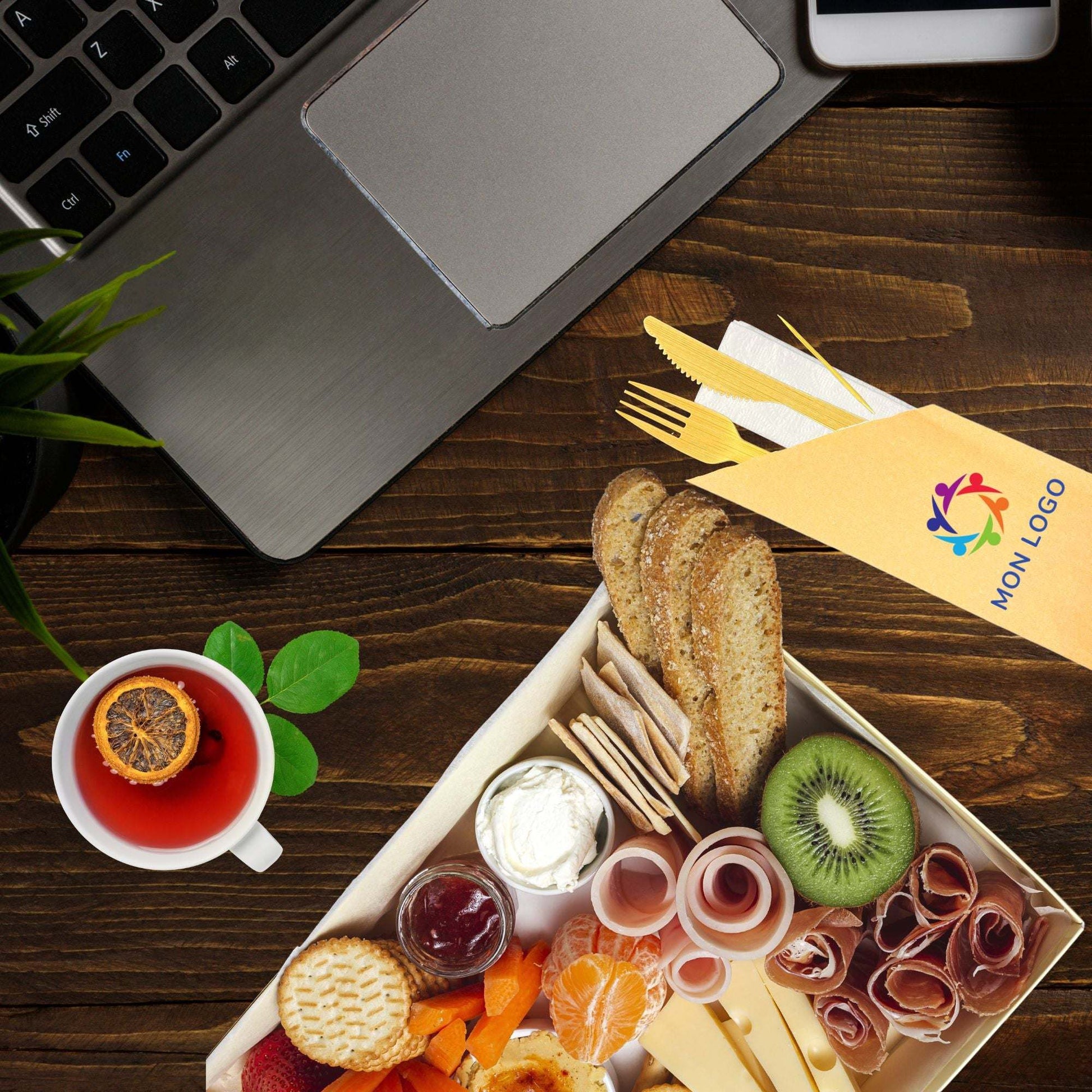 Kit couverts bambou personnalisé avec couteau, fourchette, cure-dents et serviette en papier écologique sur table.